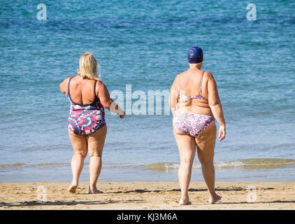 Rückansicht von älteren Frauen, die nach dem täglichen Keep-Fit-Kurs am Strand in Spanien schwimmen gehen Stockfoto