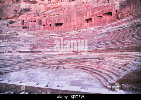 Der römischen Ära Amphitheater in die rosa Sandstein an Petra, Jordanien. die Fassaden in den Felsen gehauenen hinter sind alte Gräber. Stockfoto