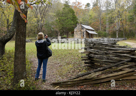 Frau fotografieren der historischen John Oliver Kabine im Herbst, Cades Cove, Great Smoky Mountains National Park, Tennessee Stockfoto