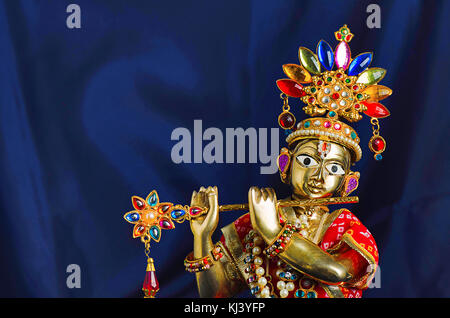 Messingstatue von Lord Krishna mit Flöte (Nahaufnahme) mit mukut oder Krone auf schwarzem Hintergrund Stockfoto