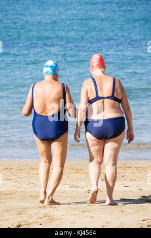 Rückansicht von älteren Frauen, die nach dem täglichen Keep-Fit-Kurs am Strand in Spanien schwimmen gehen Stockfoto