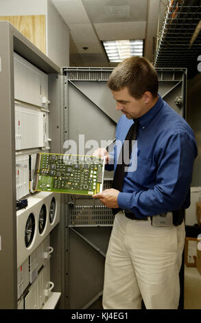 Ein Techniker wird gesehen, wie er eine Leiterplatte ersetzt, was eine wichtige Aufgabe bei der Wartung der Elektronik demonstriert. Diese Abbildung zeigt die technischen Arbeiten, die mit der Reparatur oder Aktualisierung elektronischer Systeme verbunden sind. Stockfoto