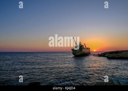 Sonnenuntergang von Schiffbruch vor Auflistung von Felsen im Meer in der Nähe von Pafos, Zypern. abend geschossen mit zwei Personen auf den Felsen geben. Stockfoto