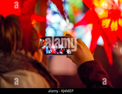 Ein Tourist nimmt ein Bild von Weihnachten Laternen an einem im Edinburgh Weihnachtsmarkt abgewürgt. Stockfoto