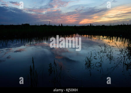 Sonnenuntergang bei bewölktem Himmel und der Reflexion über das Wasser bei Huaqiao in China Stockfoto