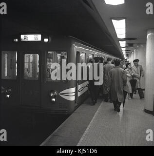 1950 s, historischen, japanischen Pendler auf einem Bahnhof Plattform boarding eine U-Bahn in Tokio, Japan. Stockfoto