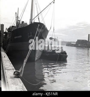 1950, historische, eine große Ladung von Zucker auf einem Lastkahn von der normannischen Königin, ein schottischer gebaut Schraube steamship günstig Dockside geladen wird. Stockfoto