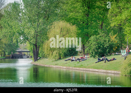 Berlin Tiergarten, Blick auf junge Leute, die sich an einem Frühlingsnachmittag am Ufer des Landwehrkanals im Tiergarten, Berlin, entspannen. Stockfoto