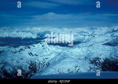 Luftaufnahme der Chugach Mountains aus einem Flugzeug, das die schneebedeckten Gipfel und das zerklüftete Gelände der Berglandschaft Alaskas zeigt. Stockfoto