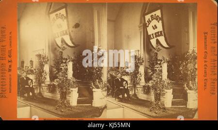 Ein Stereograph des Altars einer mährischen Kirche, der Altar ist bedeckt und Blumen und ein Banner mit der Aufschrift "Christus ist auferstanden" hängt als Teil ihrer Osterdekoration, ein Mann in einem Smoking sitzt auf einem Stuhl neben dem Altar, Lancaster, Pennsylvania, 1877. Aus der New York Public Library. Stockfoto