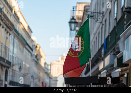 Nationalflagge innen Aussteller und die Rua Augusta arch im Hintergrund in Lissabon, Portugal Stockfoto