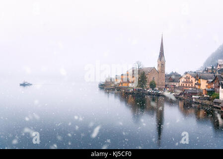 Wetter Thema Bild mit einem dichten Schneefall fallen über den Hallstätter See und Hallstatt Dorf, eines der Unesco Welterbestätten in Österreich. Stockfoto