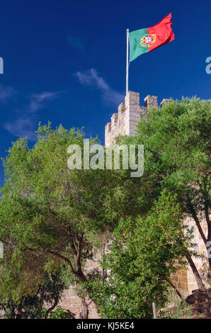 Wehende wind rote und grüne Flagge von Portugal mit Fahnenmast auf den Mauern der alten Burg namens Sao Jorge in Lissabon, Portugal. Stockfoto