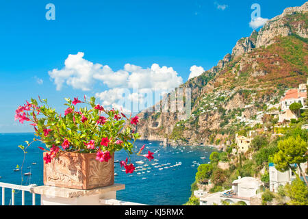 Blick auf Positano die Stadt, das Meer und die Berge vom Balkon mit Red Flower Pot im Vordergrund auf sonnigen Sommertag Stockfoto