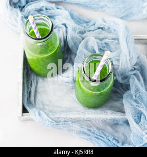 Gesunde Ernährung Konzept grüne Smoothies Frühstück auf Weiß Grau Fach blau Textil. obst gemüse saft Glas Flasche. top View Stockfoto