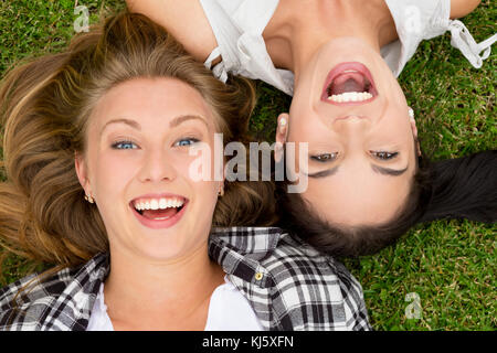 Weibliche beste Freunde, die auf dem Gras und Lachen Stockfoto