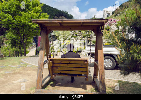 Mann in Anzug sitzt auf dem Holz Schaukeln und entspannen im schönen Park Stockfoto