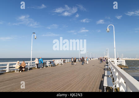 Nur wenige Menschen an der hölzernen Pier in Sopot, Polen, an einem sonnigen Tag im Herbst. Stockfoto