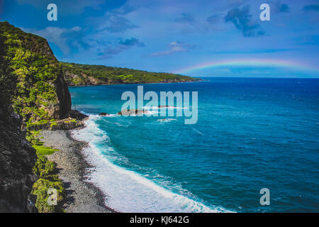 Wellen, eine Maui Beach mit einem Regenbogen in der Ferne auf dem Weg nach Hana, Maui, Hawaii Stockfoto