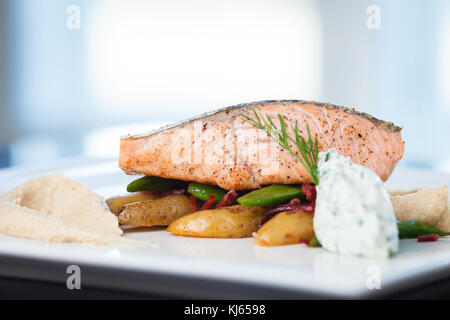 Gebackenen Lachs mit gebratenem Blumenkohl Sahne, Mandel Kartoffeln, Erbsen - chorizo Salat und Frischkäse - herb Sauce Stockfoto