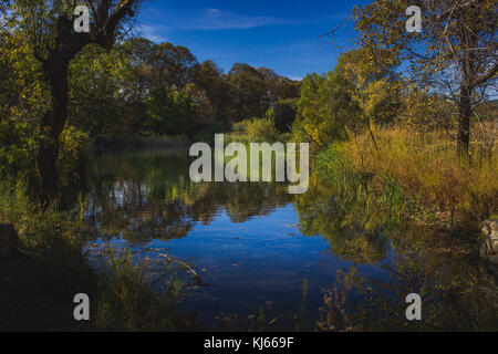 Atemberaubende Herbst Laub rund um einen kleinen See mit Reflexionen von blauen Himmel und Bäume, Eiche Glen bewahren, Oak Glen, Kalifornien Stockfoto