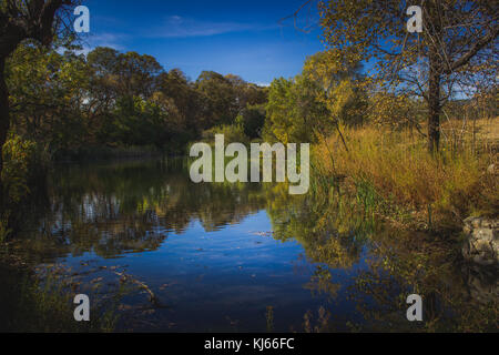 Atemberaubende Herbst Laub rund um einen kleinen See mit Reflexionen von blauen Himmel und Bäume, Eiche Glen bewahren, Oak Glen, Kalifornien Stockfoto
