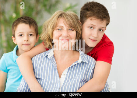 Frau mittleren Alters mit zwei Jungen im Innenbereich. Familienkonzept Stockfoto