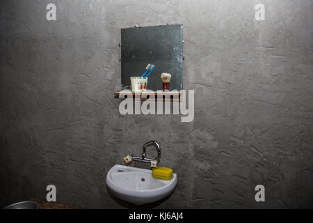 Schmutziges Waschbecken in einem alten armen Haus. Spiegel, Zahn zählen. Eine dunkle, düstere abstrakten Szene über Armut und Wohnungsnot. Stockfoto