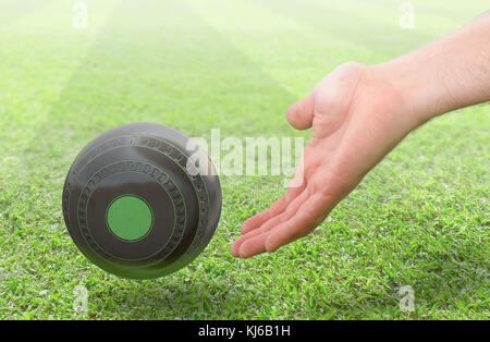 Eine männliche Hand Bowling und Freigeben einer Holz- Lawn Bowling Kugel auf einem grünen Rasen Gras Oberfläche-3D-render Stockfoto