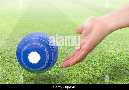 Eine männliche Hand Bowling und Freigeben einer blauen Holz Lawn Bowling Kugel auf einem grünen Rasen Gras Oberfläche-3D-render Stockfoto