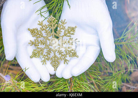 Hände in Handschuhe halten künstliche Schneeflocke Stockfoto