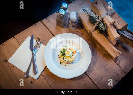 Russische traditionelle Salat Olivier auf hölzernen Tisch Stockfoto