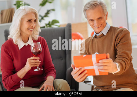 Liebevolle Frau zu Mann erhalten über Geschenk aufgeregt suchen Stockfoto