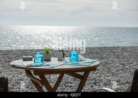 Bistro Tisch am Kiesstrand in Nizza, Frankreich. Stockfoto