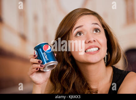 Quito, Ecuador, 06. Mai 2017: Lächelnde junge Frau, die einen pepsi in einem verschwommenen Stadthintergrund hält Stockfoto