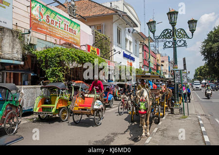 Zyklus Rikschas/becak und Pferdekutschen für den öffentlichen Verkehr in der Jalan Malioboro, wichtigsten Einkaufsstraße in Yogyakarta, Java, Indonesien