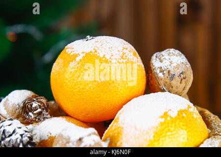 Mandarinen, Nüsse und Stösse in einem Korb auf dem Hintergrund einer Weihnachtsbaum Stockfoto