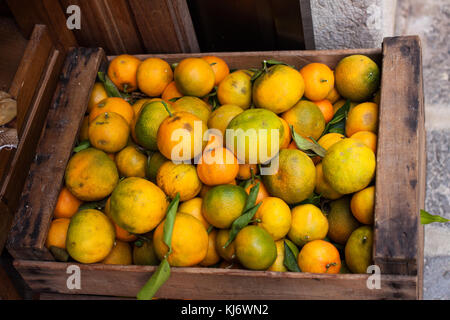 Holzkiste von grünlich Mandarinen (tangerins) mit grünen Blättern zum Verkauf Stockfoto