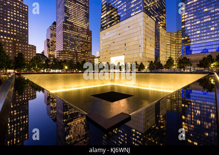 Im Norden einen reflektierenden Pool bei Dämmerung mit Blick auf das One World Trade Center beleuchtet. Lower Manhattan, 9/11 Memorial and Museum, New York City