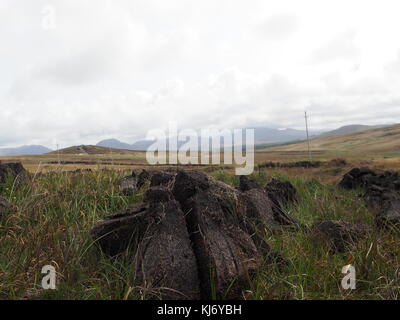 Trocknen von Klümpchen Torf in einem Feld in Irland an einem bewölkten Tag Stockfoto