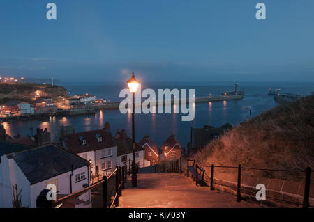 Blick auf die Küstenstadt Whitby in North Yorkshire bei Dämmerung, Blick auf die Hafenmündung von den 199 Stufen, an einem Oktoberabend. Stockfoto