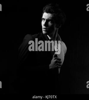 Denken Depression charismatische Mann suchen, um sich über dunkle Schatten dramatischen Licht Hintergrund. Closeup Portrait. Schwarz und Weiß. Stockfoto