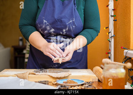 Junge kaukasier Frau hinter einem Tisch, Backen für Weihnachten. Hält sie raw-Cookie in der Form von Star. Stockfoto
