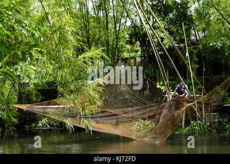 Asiatischer Mann ausbessern einen Aufzug Fischernetz an einem Fluss in Vietnam. Stockfoto