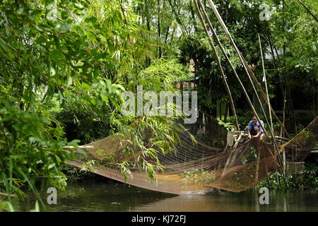 Asiatischer Mann ausbessern einen Aufzug Fischernetz an einem Fluss in Vietnam. Stockfoto