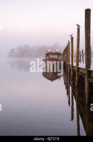 Boot von einem Holzsteg an einem nebligen Morgen im Herbst derwentwater im Lake District, Keswick cumbria England Großbritannien Stockfoto