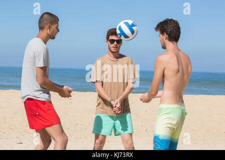 Junge Männer spielen Volleyball am Strand Stockfoto