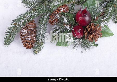 Immergrüner Baum Zweig mit kiefernzapfen und christmas Ornament auf verschneiten weißer Hintergrund Stockfoto