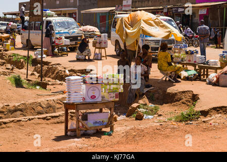 Frauen sitzen durch ihre kleinen Stände waren verkaufen am Straßenrand in einer geschäftigen Stadt, Busia, Uganda, Ostafrika Stockfoto