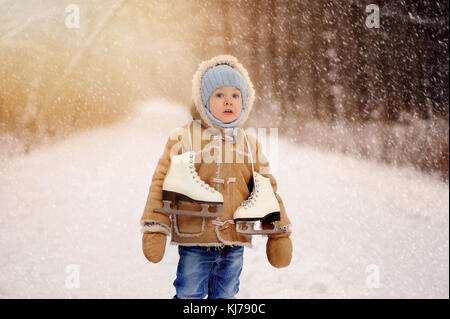 Eine schöne, vier Jahre alten Jungen tragen Schaffellmantel spielen auf verschneiten, Winter Forest Road Stockfoto